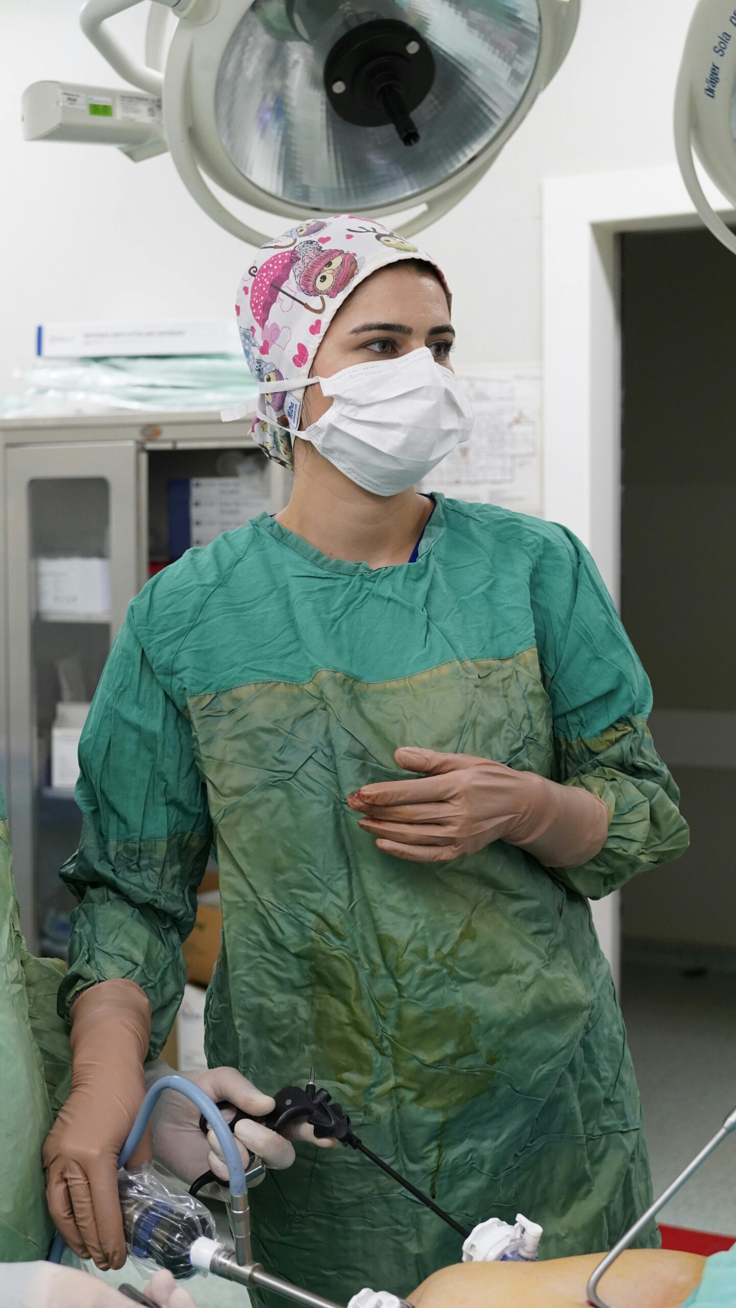 Nurse in surgical attire in an operating room, focused on a medical procedure.